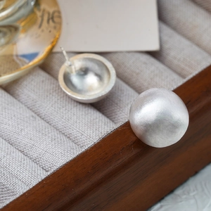 Macro shot of silver matte spherical studs with brushed texture on grey jewelry box