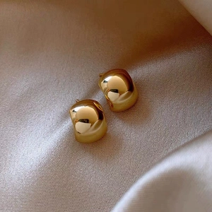Close-up of golden square stud earrings on champagne silk background for luxury texture