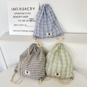 Close-up of drawstring plaid canvas backpacks with cartoon labels and colorful beads