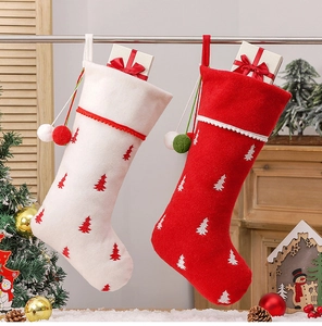 Detail of red and white Christmas stockings with embroidered trees and fluffy pom poms