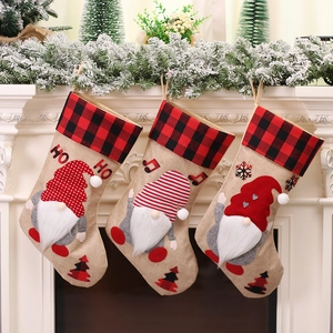 Three Christmas stockings with plaid cuffs and 3D gnome figures hanging on a white fireplace