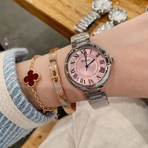 Close-up of elegant silver steel watch with pink Roman dial and chic bracelet layering