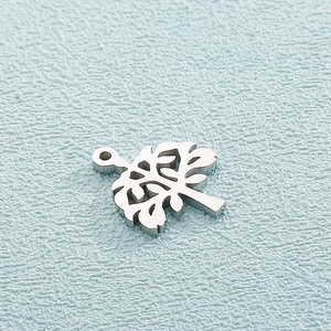 Close-up of polished silver stainless steel tree of life pendant on a light blue background