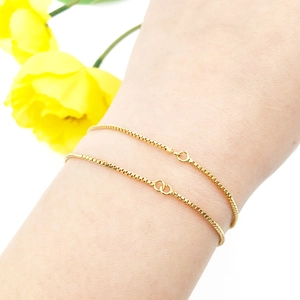 Close-up of golden box chain bracelet with double ring clasp on woman's wrist