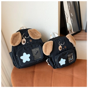Detail of two black puppy backpacks with blue star embroidery on a striped sofa