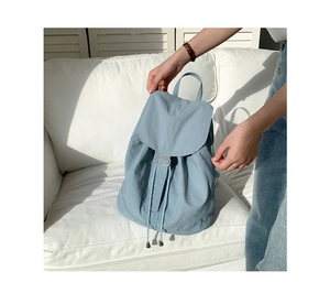 Dettaglio dello zaino in nylon azzurro con fibbie argentate e tasche laterali
