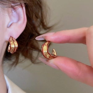 Detail of gold and red drop earrings with irregular textures shown on model and close-up