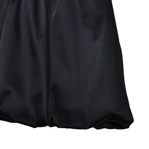 Detailed macro view of the black satin dress with a stylish bubble hem and glossy finish