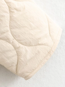 Close-up of wave-quilted fabric texture on a beige casual cotton jacket for winter