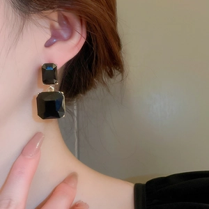 Detail of double black square crystal earrings on model with golden claw settings