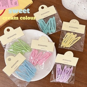 Close-up of matte cream-colored hair clips set in transparent packaging with card