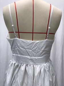 Detail of white pleated dress showing adjustable spaghetti straps and waist ruching