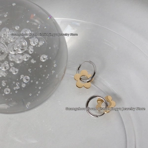 Detailed close-up of daisy hoop earrings with gold petals on a transparent glass tray