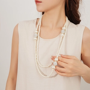 Detailed view of layered faux pearl necklace with sparkling rhinestone spheres on model