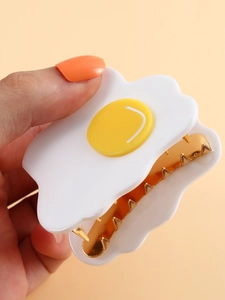 Close-up of a poached egg hair claw clip with a white cloud base and yellow yolk detail