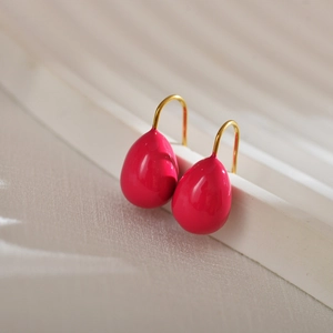 Elegant fuchsia teardrop enamel earrings with gold hooks on a white display stand