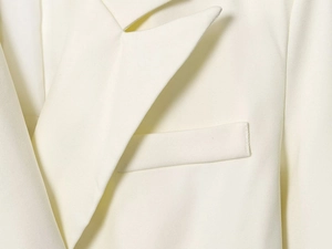 Close-up of white double-breasted blazer showing fine fabric texture and lapel stitching