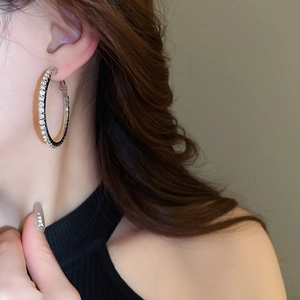 Close-up of sparkling oversized silver hoop earrings with rhinestones on a female model