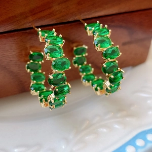 Dettaglio macro dei cristalli smeraldo ovali su cerchi in argento dorato