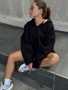 Détail du sweat à capuche noir oversize avec imprimé rouge et blanc dans la capuche