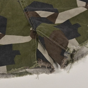 Gros plan d'un short camouflage avec ourlets effilochés et détails de couture en coton