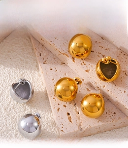 Detail of PVD electroplated gold and silver ball stud earrings on stone texture