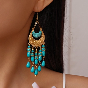 Detailed macro view of bohemian crescent moon earrings with turquoise beads and golden tassels