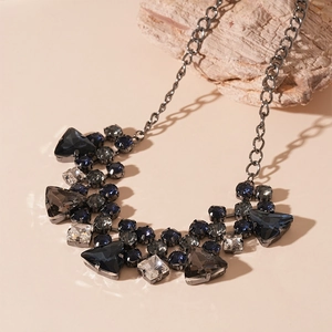 Detailed view of geometric dark blue and grey rhinestones on a chunky gunmetal necklace