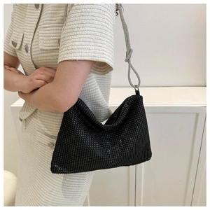 Close-up of black rhinestone shoulder bag with silver chain strap on white outfit