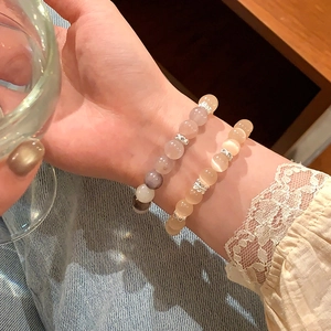 Dettaglio di braccialetti con perline occhio di gatto rosa e beige con distanziatori argento