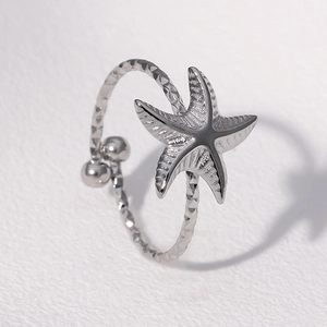 Détail d'une bague étoile de mer argentée avec anneau martelé sur fond clair