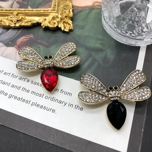 Detail of vintage gold dragonfly brooches with red and black crystal teardrops on a book