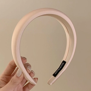 Detail of light pink satin padded headband featuring a woven handmade label
