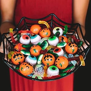 Black spider web candy bowl filled with Halloween sweets held by a person in a red dress