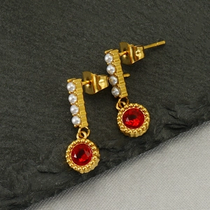 French style gold pearl earrings with red round crystal on a grey stone background