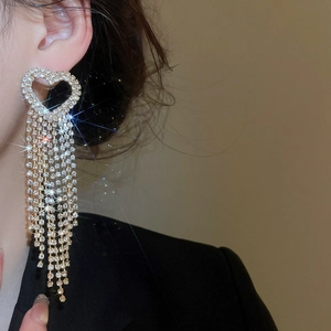 Detailed view of silver heart earrings with long crystal tassels on a model