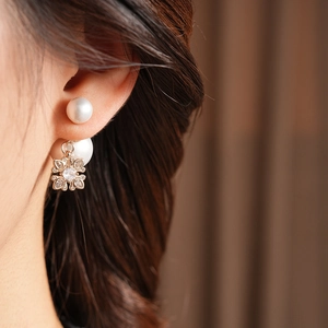 Close-up of pearl earrings with golden snowflake pendants and clear cubic zirconia stones