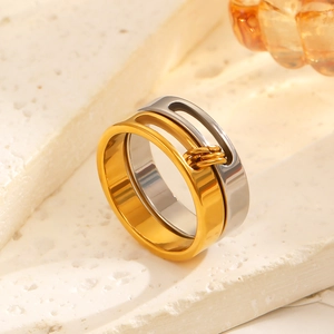 Detail of minimalist gold and silver tiered rings on a natural stone surface