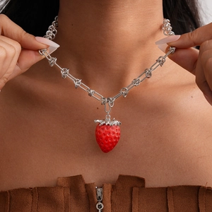 Close-up of asymmetrical necklace featuring a red resin strawberry charm and knotted chain