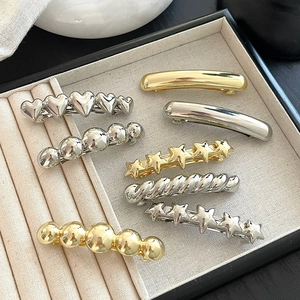 Fermagli per capelli minimalisti in oro e argento a forma di cuore e stella su un vassoio