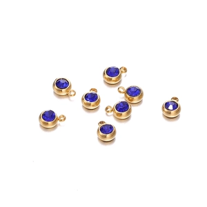 Vue macro de breloques en acier doré de 6mm avec pierres de naissance en zircon bleu