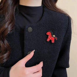 Detail einer roten Strass-Pferdebrosche auf einer schwarzen Jacke für eleganten Kontrast