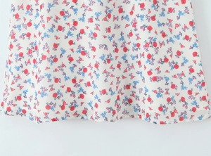 Detail of white floral A-line mini dress showing red and blue embroidery patterns