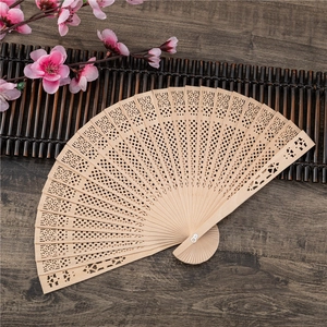 Eight-inch open hollowed sandalwood folding fan with sunflower pattern on wood table