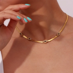 Golden flat snake chain necklace featuring evil eye pendants with black and white stones