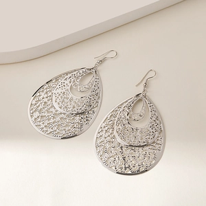 Close-up of silver hollow floral teardrop earrings with multi-layer geometric metal design