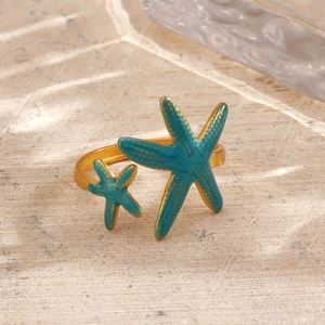 18K gold plated starfish ring with turquoise enamel dots on a beach sand background