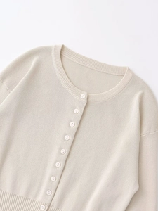 Close-up of beige knit cardigan showing round neck and smooth button details
