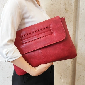 Close-up of red PU leather clutch bag with a large flap and textured embossed pattern