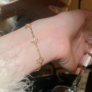 Nahaufnahme eines goldenen Armbands mit funkelnden Zirkonia-Kreuzanhängern am Handgelenk